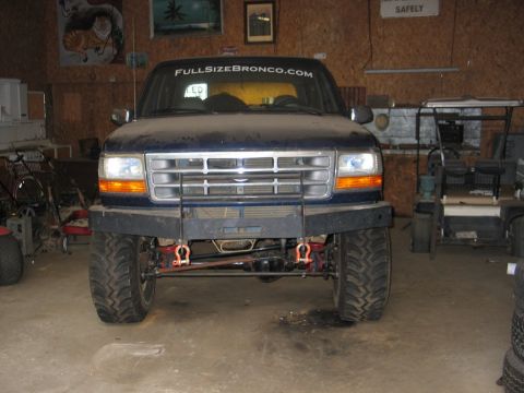 1995 Ford Bronco - This dark blue SUV features an aftermarket bumper and large tires, with a "FULLSIZEBRONCO.COM" sticker on the windshield.