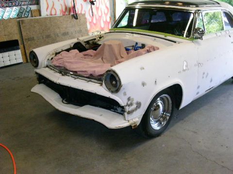 1954 Ford Crestline - A 1954 Ford Crestline sedan is shown in a garage, undergoing repairs with its hood open and bodywork visible.