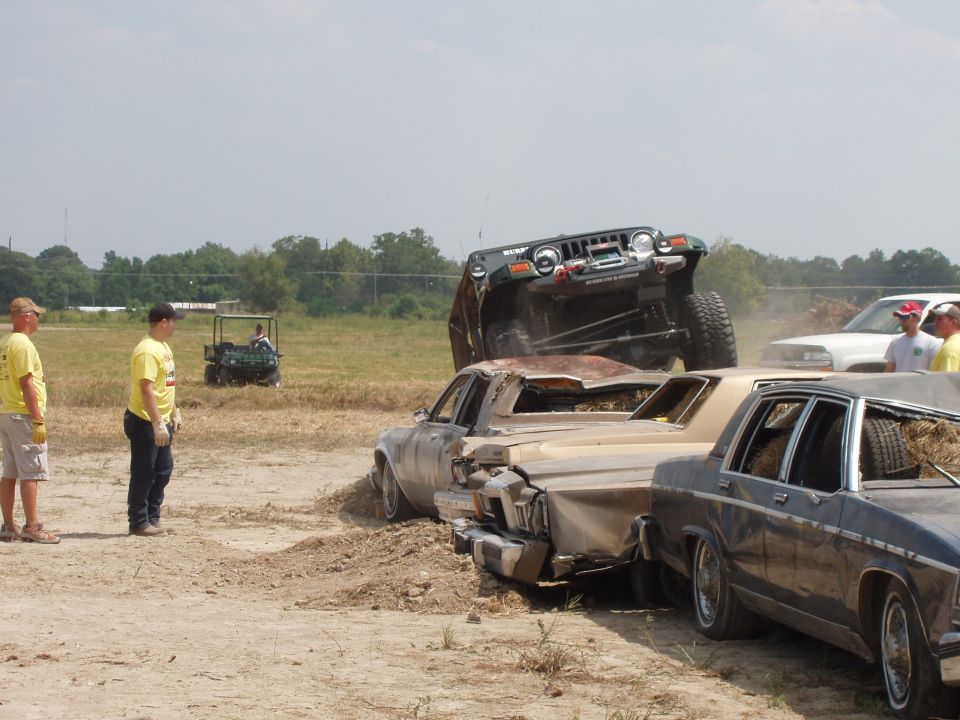 Jeep on top of crushed cars in a demolition derby