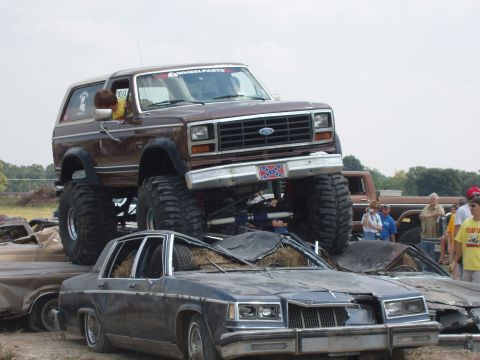 2000 Chevrolet Tahoe - This lifted Ford Bronco is crushing cars in a junkyard setting.