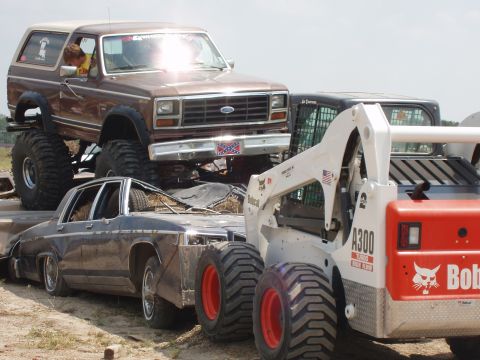 2000 Chevrolet Tahoe - A lifted 1980 Ford Bronco is loaded onto a trailer with other vehicles and equipment.