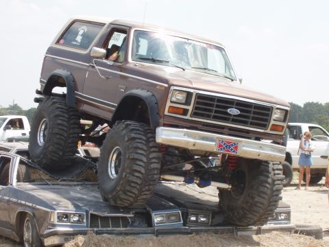 2000 Chevrolet Tahoe - Modified Ford Bronco crushing other vehicles, with a visible Confederate flag decal on the front bumper.