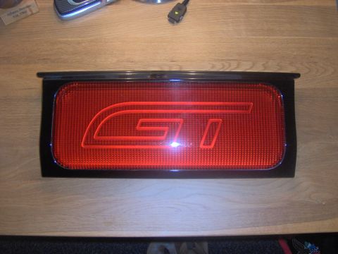1994 Ford Probe - A red taillight assembly with a prominent 'GT' emblem is shown on a wooden surface.