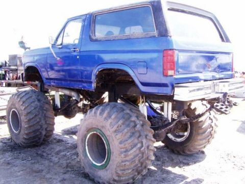 1979 Ford Bronco - This modified blue truck features oversized tires and a lifted suspension, giving it a monster truck appearance.