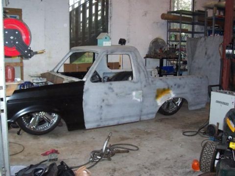 1979 Ford Bronco - A truck body in a garage, undergoing repairs and modifications with exposed parts and tools around.