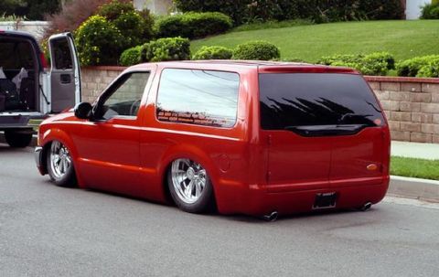 1979 Ford Bronco - A red SUV with a custom lowered suspension and chrome wheels is parked on a street.