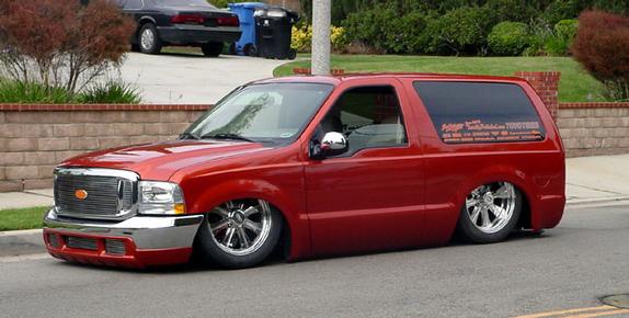 Red custom SUV with chrome wheels and slammed suspension, side view