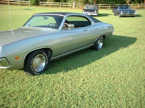 1971 Ford Torino - A silver 1971 Ford Torino coupe with a black vinyl roof is parked on a grassy lawn alongside two other classic cars.