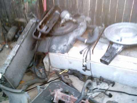 1986 Ford Bronco - Various engine components are piled together in front of a wooden fence.