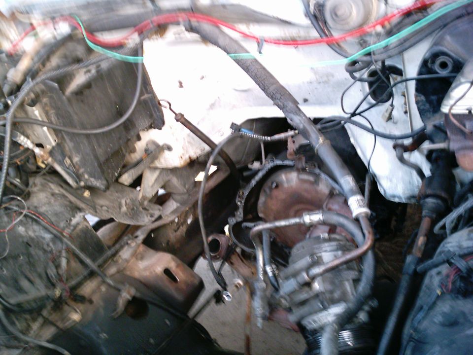 Stripped truck engine bay with engine removed, loose wiring, radiator and A/C compressor
