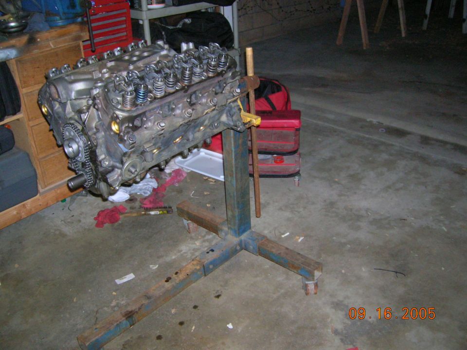 Engine block on a blue metal stand, with a chain and gears visible on the left side
