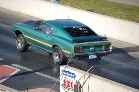 2005 Ford Deluxe - A green 1969 Ford Mustang Mach 1 with louvers and a yellow stripe races down the drag strip.