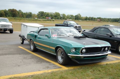 2005 Ford Deluxe - A classic green Mustang Mach 1 is parked next to other vehicles at an outdoor event.