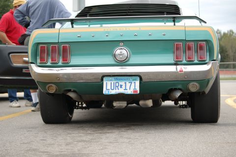 2005 Ford Deluxe - Rear view of a green 1969 Ford Mustang Mach 1 with gold racing stripes and large rear tires.