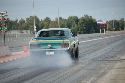 2005 Ford Deluxe - Rear view of a teal 1969 Ford Mustang Mach 1 performing a burnout at a drag strip.