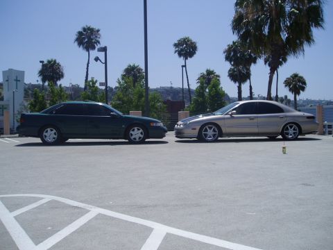 1993 Ford Taurus - Two sedans parked side-by-side in a parking lot with palm trees in the background.