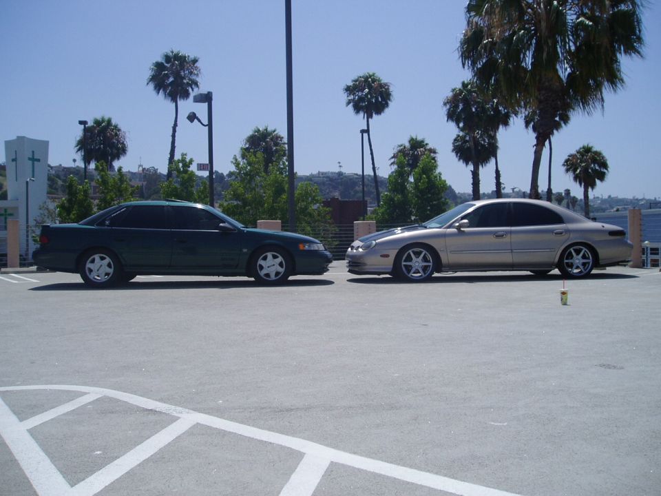 Two sedans parked facing each other, one dark green, one gold with black hood stripe