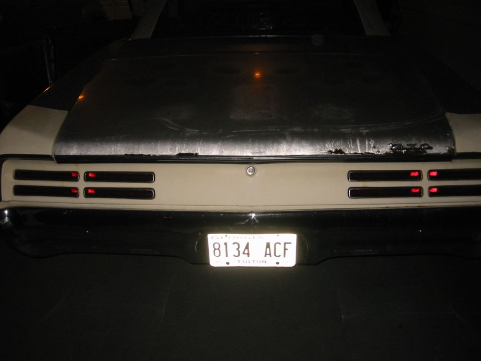 Rear of white muscle car at night with quad slot taillights and Georgia plate