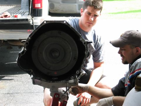 1995 Ford Bronco - Two mechanics examine a transmission assembly during a repair.