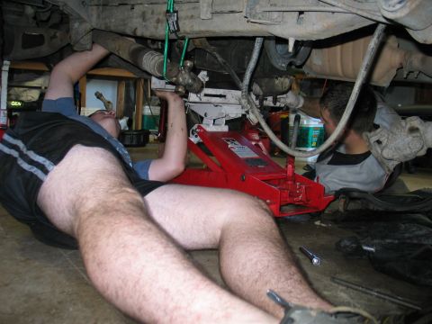 1995 Ford Bronco - Two mechanics are performing maintenance on the undercarriage of a vehicle.
