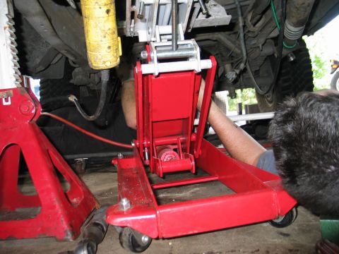 1995 Ford Bronco - Working on the underside of a vehicle, using a jack and jack stands for support.