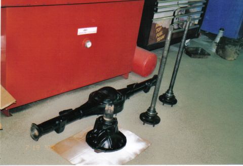 1986 Ford Bronco - Rear axle assembly and axle shafts laid out on the floor.