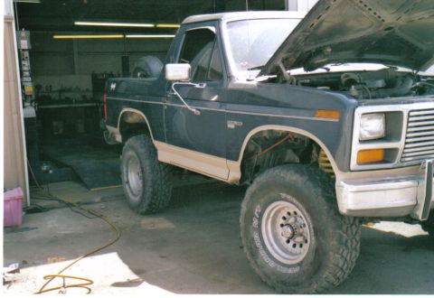 1986 Ford Bronco - This Ford Bronco is in a garage with its hood open, showing the engine bay.