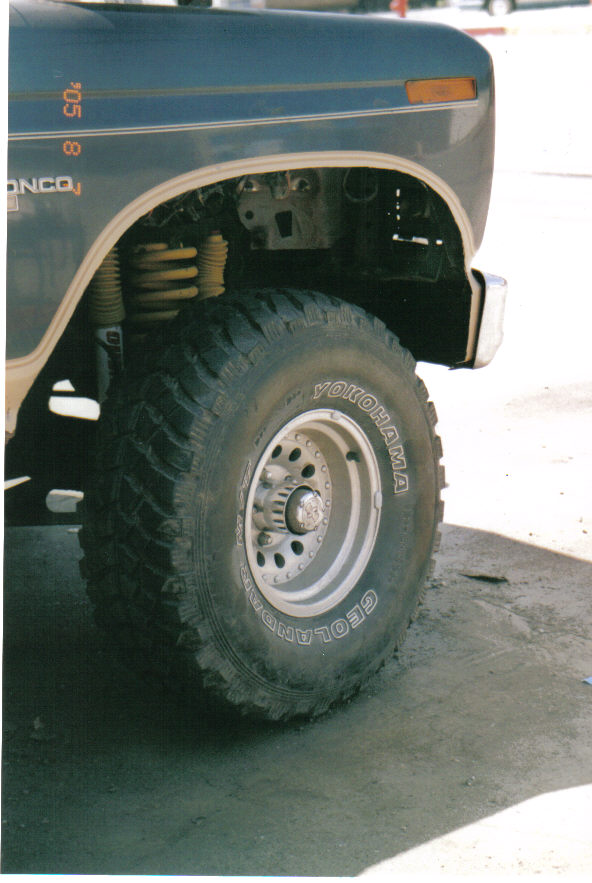 Dark blue Ford Bronco front fender and wheel with Yokohama Geolander tires. Cut fenders are visible