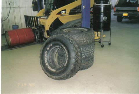 1986 Ford Bronco - Tires and equipment in a garage setting, with a Ford Bronco in the background.