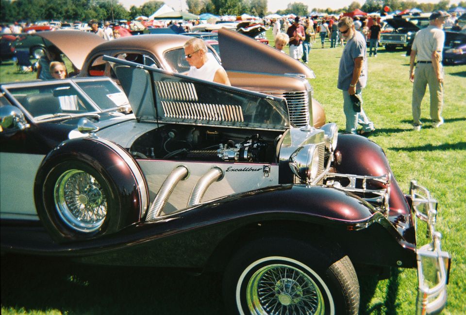Maroon Excalibur car with hood open, showing engine and side pipes