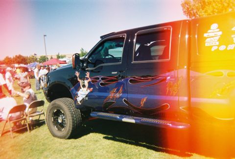1972 Ford Ranchero - A black pickup truck with custom flame graphics is parked on a grassy field at an outdoor event.