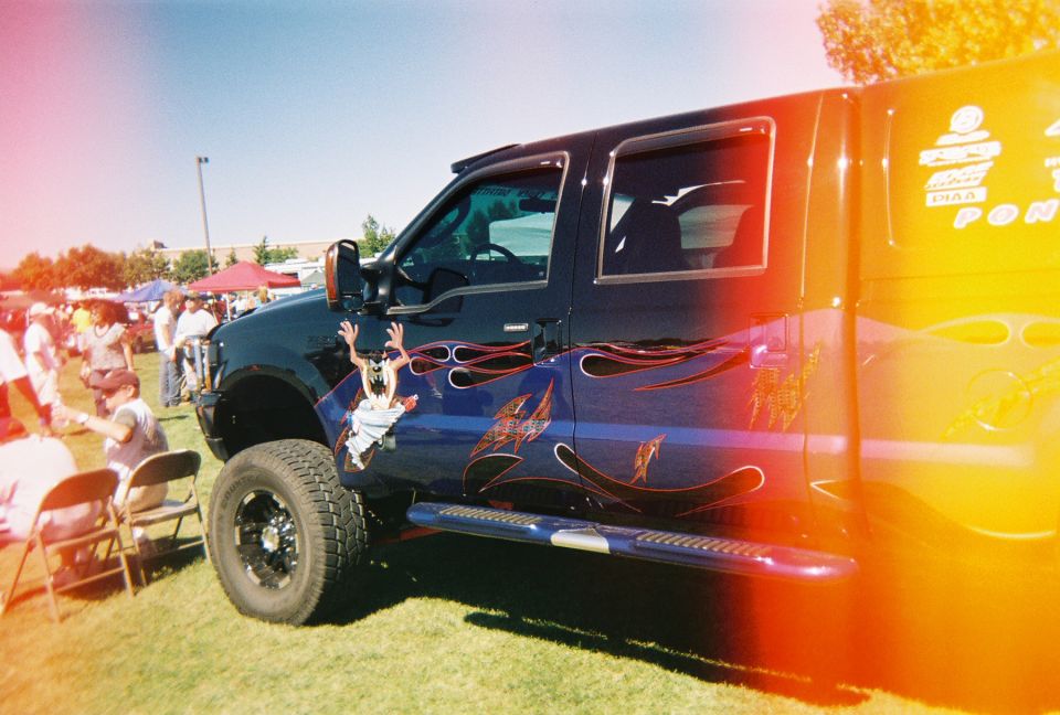 Black pickup truck with flame graphics and a cartoon character on the door
