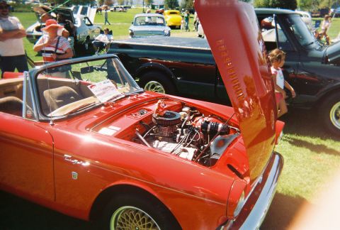 1972 Ford Ranchero - Outdoor car show features a red convertible with its hood open, alongside other vehicles.