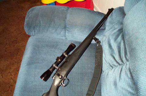 1988 Ford Bronco - A rifle with a scope and sling is placed on a blue upholstered surface.