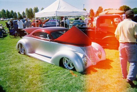 1972 Ford Ranchero - A custom hot rod coupe with its hood raised sits on display at an outdoor car show.