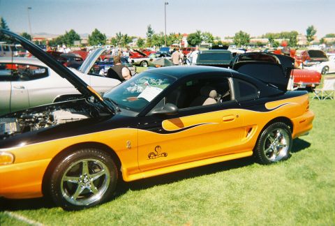 1972 Ford Ranchero - Orange and black Ford Mustang Cobra with flames graphic at a car show.