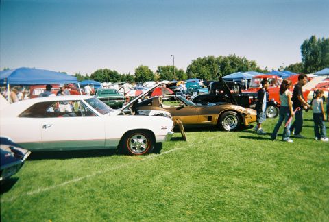 1972 Ford Ranchero - Several classic cars are on display at an outdoor event, with people milling about on a sunny day.