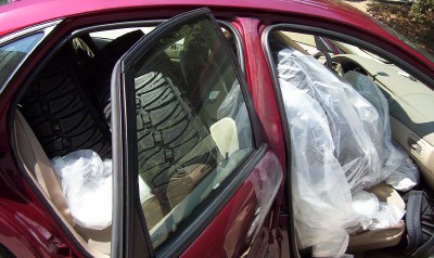 1995 Ford Bronco - Tires and items are loaded into the interior of a red car, obscuring most of the cabin.
