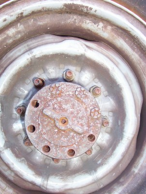 1995 Ford Bronco - Close-up view of a rusty wheel hub with lug nuts and a portion of the tire rim visible. The 'SUPER MOTORS' watermark is present at the bott…