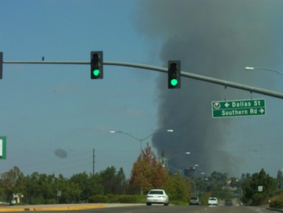 1995 Ford Bronco - A plume of dark smoke billows into the sky behind traffic lights on a clear day.