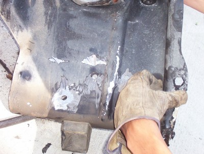 1995 Ford Bronco - A gloved hand holds a rusty metal part that has been repaired with welds.