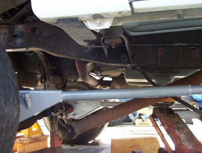 1995 Ford Bronco - The undercarriage of a vehicle is shown, supported by jack stands, revealing its mechanical components.