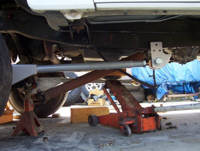 1995 Ford Bronco - Vehicle's undercarriage is supported by jack stands and a hydraulic jack, indicating maintenance or repair work.