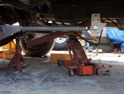 1995 Ford Bronco - Underbody view of a vehicle undergoing maintenance, supported by jack stands and a floor jack.