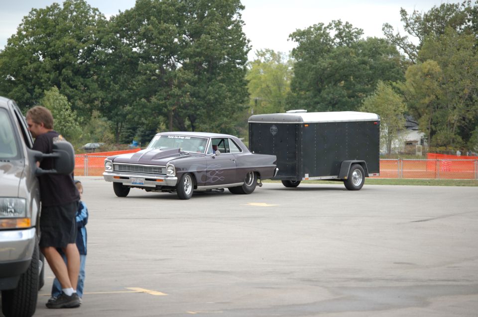 Purple 1966 Chevy Nova drag car with flames towing a black enclosed trailer
