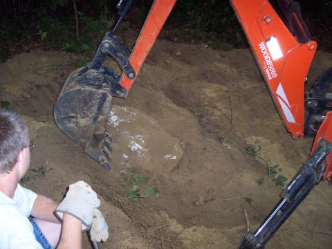 2001 Ford Crown Victoria - An excavator is used to dig into a mound of dirt, with a person observing the work.