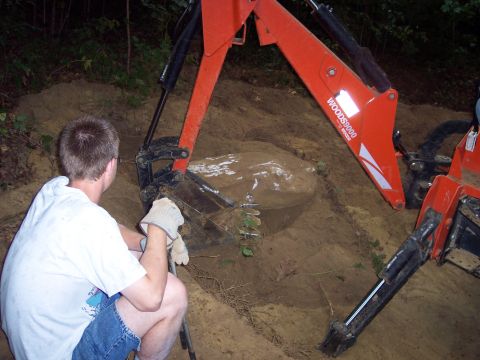 2001 Ford Crown Victoria - A person watches as an orange tractor loader digs into a mound of dirt.