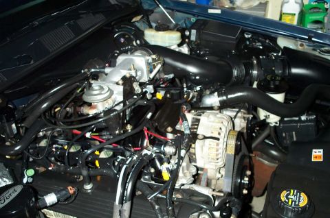 1998 Ford Crown Victoria - The engine bay of a 1998 Ford Crown Victoria, showing the air intake system and alternator.