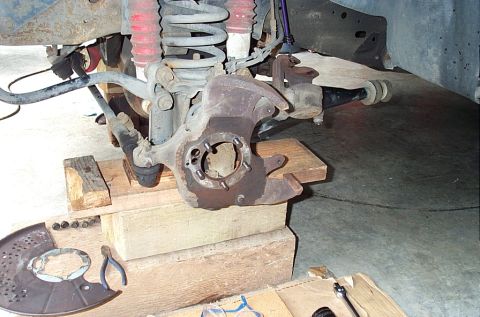 1995 Ford Bronco - A front steering knuckle stripped bare on a lifted 4x4, spindle, hub and rotor removed, leaving the bolt studs and open bore visible, with…