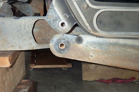 1995 Ford Bronco - Underbody shot of the rear ends of two rusty radius arms, each with the old bushing gone and a bare sleeve/washer left in the mounting eye…